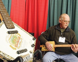 Ed Wentling of Farrell, Pa., demonstrates one of his cigar-box guitars at the Holiday Craft & Gift Show at Eastwood Expo Center in Niles. He has built more than 200 of the instruments that are patterned after guitars from the American southern bayou. His company is called Bayou Blues Guitars. He was at the show, which ran Friday through Sunday.
