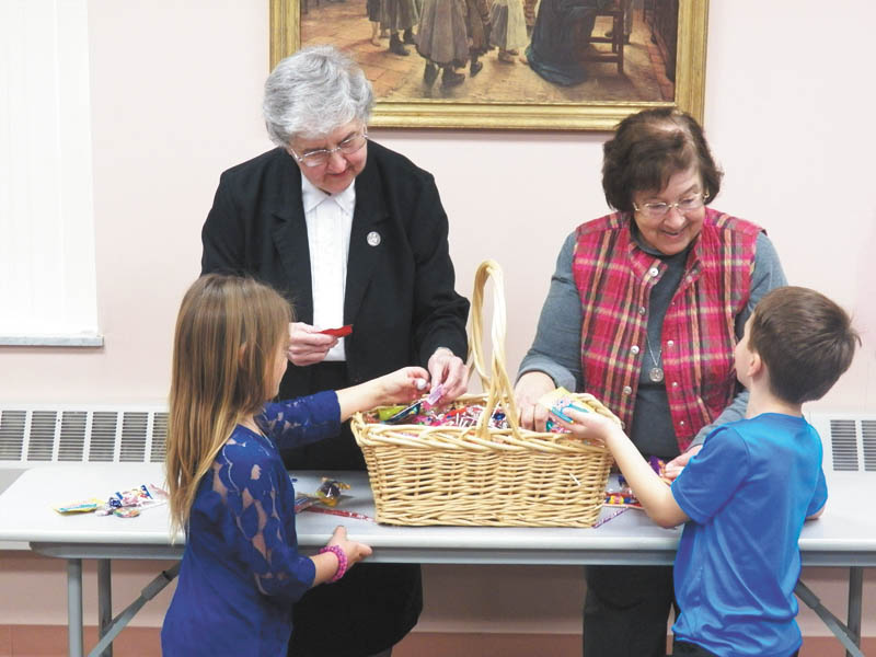 SPECIAL TO THE VINDICATOR
Ursuline Preschool and Kindergarten in Canfield has begun a Caring is Sharing candy campaign. Two moms, Nicole Billack of Canfield and Kris Oddis of Boardman, came up with a way to give much of the extra candy in their homes to children in need. Sojourner House and the Juvenile Justice Center agreed to accept the surplus. In the foreground Riley Billack, in kindergarten, left, and Ben Oddis, in transitional kindergarten, admire some of the candy that was collected with Sister Mary Dunn, left, and the school principal, Sister Charlotte Italiano.
