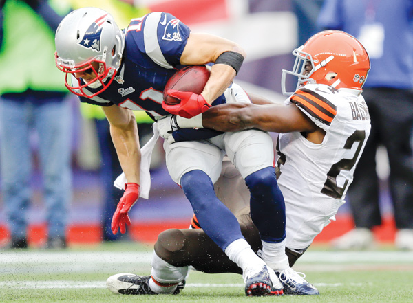 Cleveland Browns cornerback Johnson Bademosi, right, tackles New England Patriots wide receiver Julian Edelman after a catch in the second quarter of Sunday’s game in Foxborough, Mass.