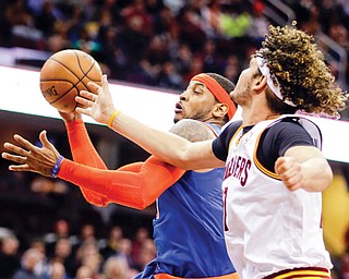 New York Knicks’ Carmelo Anthony, center, grabs a rebound against Cleveland Cavaliers’ Anderson Varejao of Brazil in the second quarter of an NBA game Tuesday in Cleveland.