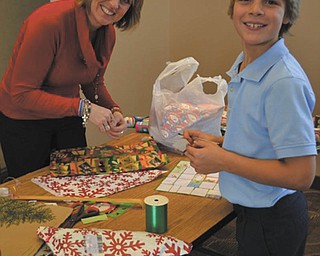 SPECIAL TO THE VINDICATOR:
Students at Holy Family School in Poland recently enjoyed shopping at Santa’s Workshop. Several small good quality gifts were available for purchase. Lisa Daprile, left, parent volunteer, wrapped the gifts that third-grader T.J. Richey bought for his family at the workshop.