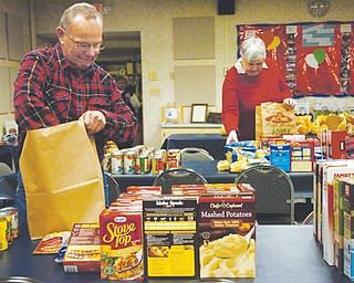 Dave Sylak, a member of St. Mary Church, and Carol Seifert, a member of Mineral Ridge Church of Christ, pack Christmas grocery bags Monday for distribution by Mineral Ridge Community Parish Association on Tuesday. The association helps those in need in Mineral Ridge and those who are members of association churches.
