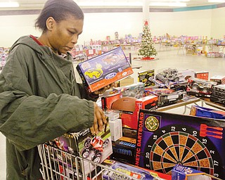 Nikesha Curry of Youngstown looks for Christmas gifts for her children in the toy section at the Salvation Army’s
distribution center in the Austintown Plaza on Mahoning Avenue. Families who have not registered for a shopping
day at the center can still sign up from 1 to 3 p.m. Friday .
