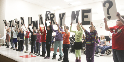 William D. Lewis The Vindicator Students at Girard IntermediAte School hold up cards spelling out Will You Marry Me? while 5 th grade teacher Joe Carbon proposes to fellow 5th grade teacher Alyssa DiBernardi during a 12-20-13 asembly at the school.