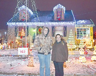 Chuck Dressel and his fiancee, Jenn Rogers, of Youngstown pose outside their home on Hazelwood Avenue. Dressel has put on a show for six years and now has the lights timed to music. “Our display focuses on everything,” Dressel said. “I don’t want to focus all on lights.”