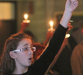 William D Lewis The Vindicator Grace rusko, 11, of Canfield holds a candle and sings Silent Night during Christmas Eve service at Western Reserve United Methodist Church in Canfield.