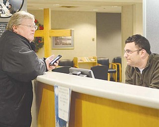 Jason Axelson, a volunteer with B’nai B’rith and Operation Snowflake, greets visitor Eric Ronan at St. Elizabeth Health Center in Youngstown. Members of the Jewish service organization and others volunteered at the information desk and the gift shop on Christmas Day to give Christian workers the day off .