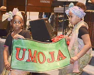 Melea Lewis, left, and Amira Monserrat hold a sign reading “Umoja,” which means unity, during a celebration for the first night of Kwanzaa at New Bethel Baptist Church on Thursday. Three other Youngstown churches also will host Kwanzaa celebrations in the next week.