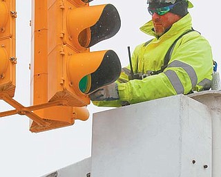 Jimmy Clacko with the city of Youngstown’s traffic engineers department replaces a burned out bulb on a traffic signal at Delason and Oak Hill avenues on the South Side. Clacko said a lot of lights burn out due to cold weather.