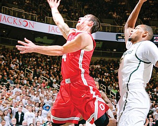 Ohio State’s Aaron Craft puts up a layup against Michigan State’s Adreian Payne during the first half of their NCAA basketball game Tuesday in East Lansing, Mich. The No. 5 Spartans edged the No. 3 Buckeyes, 72-68, in overtime.