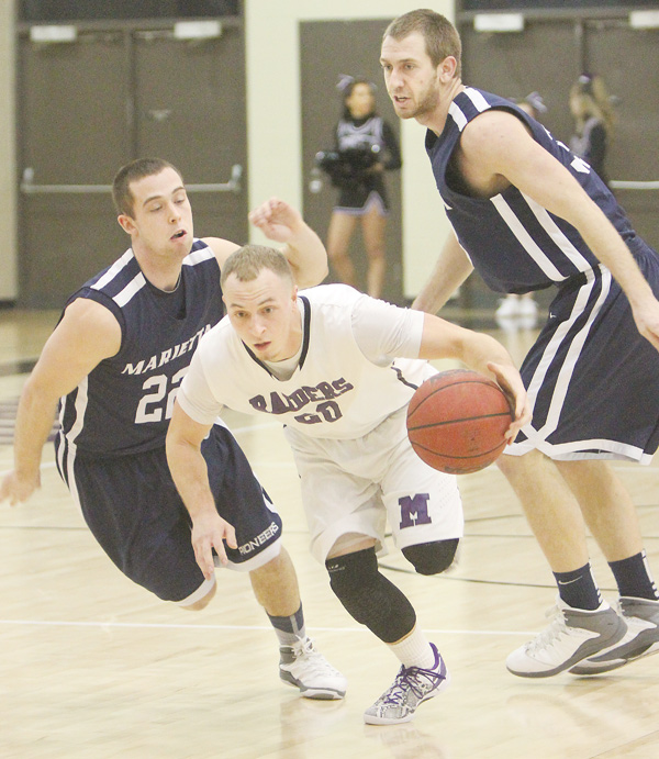 Mount Union’s Nate Jacubec, a Struthers graduate, drives through Marietta defenders Brennan McKean (22) and Andy Stegman (33) during a game Wednesday at Mount Union in Alliance. The Purple Raiders edged the Pioneers, 73-72.