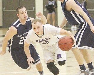 Mount Union’s Nate Jacubec, a Struthers graduate, drives through Marietta defenders Brennan McKean (22) and Andy Stegman (33) during a game Wednesday at Mount Union in Alliance. The Purple Raiders edged the Pioneers, 73-72.