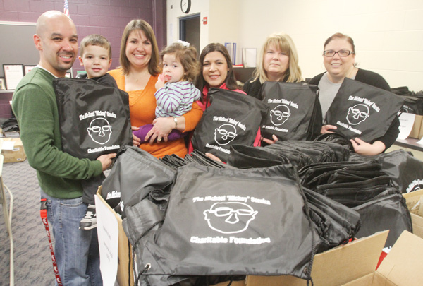 Posing with school-supply bags to be distributed to students in Campbell City Schools are members of The Michael “Mickey” Soroka Charitable Foundation, from left, Eric Gonzalez, holding son, Gavin, 4; Carmel Gonzalez, Eric’s wife, holding their daughter, Elena, 1; Jennifer Kavouras, Rena Regula and Andrea McGoogan. Foundation members gathered Wednesday to fill bags to be distributed district wide Friday, weather permitting. The foundation was founded to carry on the legacy of Soroka, a Campbell High School teacher who went out of his way to help students whether they were enrolled in his classes or not. Soroka died in 2011 at age 49.