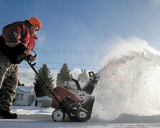 Norm Capp of Youngstown, bundled up as he braves the conditions Monday, uses a snowblower to clear a friend’s driveway on Chaney Circle in Youngstown. Today’s high temperature is expected to be 2 degrees with wind chills as low as 28 below zero.