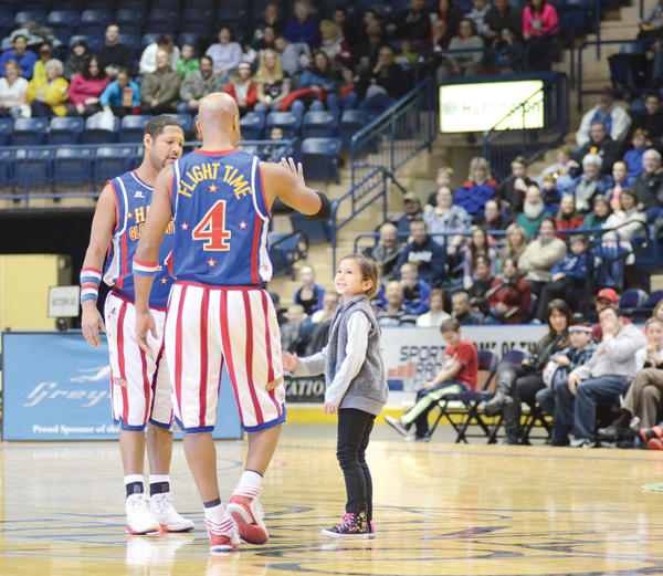 The Harlem Globetrotters “Handles” and “Flight Time” invite Maria Goske, 6, out onto the court to teach her a few basketball tricks during Wednesday’s performance at the Covelli Centre.