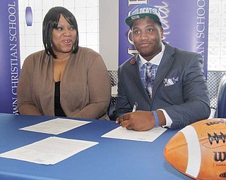 Kambria Brown, watches as her son, Youngstown Christian defensive lineman Tymere Dubose, signs his
letter of intent to play football for the University of Kentucky during a ceremony at the high school Wednesday.
Joining Dubose on the Wildcats’ squad will be Niles offensive lineman Josh Krok.