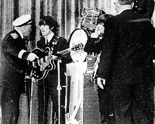 Police Inspector Carl Bear of Cleveland's Juvenile Bureau, left, orders George Harrison and the other members of the British pop group The Beatles, off the stage of the Public hall, Cleveland, Ohio, Sept. 16, 1964 as teenagers rushed the stage. Bear let the group back on ater wailing youngsters were given 15 minutes to cool down. From left to right, Bear, Harrison, John Lennon, unknown, and Ringo Starr, top right. (AP Photo)