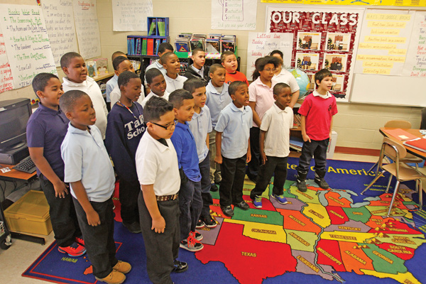 Laurie McEwan’s fourth-grade class, above, performs the school song Monday. Each class will sing the song, and a panel of judges will narrow down the competition until a winner is identified.