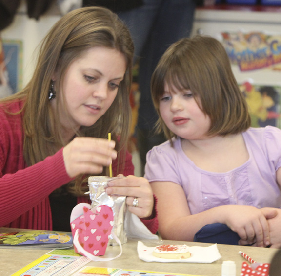 William D.Lewis The Vindicator Austintown Elem school kindergarten teacher Jen Kalouris helps student Emily with a Valentines craft project a Valentines day party at the school 2-13.