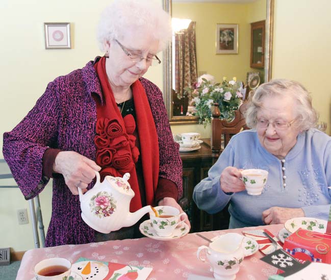 Eunice Hall, left, pours tea as Edith Cardelein looks on during a recent gathering for several women from England. For more than 50 years, a group of English women who all moved to the Youngstown area at least six decades ago often get together and have tea.