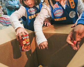 Mia Rucci, 7, left, and Haley Shiley, 7, put cans of food into a box that will be delivered to Second Harvest Food Bank. Their Girl Scout troop teamed up with some respiratory-therapy students at Youngstown State University to collect the food.
