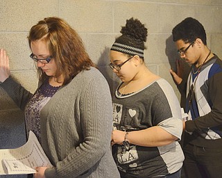 Joann Collins and her two children — 12-year-old Antonette Bell and 16-year-old Derrick Bell — place their hands upon a wall to bless their new home during a Habitat for Humanity housed edication ceremony Sunday.