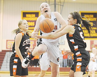 Canfield’s Rachel Tinkey is fouled driving to the basketball by Green defender McKenzie Black during the second half of their Division I district semifinal Monday at the Walsh University Alumni Arena in North Canton. The Cardinals edged the Bulldogs, 41-38, in overtime to advance to the final Friday against the winner of tonight’s contest between Perry and Hoover.