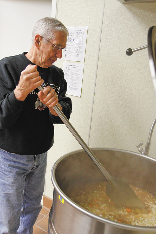 Mike Devine, who volunteers with his wife, Ellen, with the John Severn Soup Group at St. Dominic Church in
Youngstown, stirs ham, barley and potato soup in a 30-gallon kettle. The church group makes about 25
gallons of soup every Monday from October through April for St. Vincent de Paul dining hall.