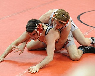 COLUMBUS, OHIO - FEBRUARY 28, 2014: Korey Frost of Canfield holds on to the leg of Dustin Warner of Uhrichville Claymont as the two wrestle on the mat during their 120lb championship bracket bout during the 2014 division 2 state wrestling tournament at Schottenstein Center.
