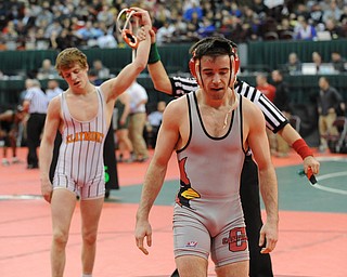 COLUMBUS, OHIO - FEBRUARY 28, 2014: Korey Frost of Canfield walks off the mat while Dustin Warner of Uhrichsville Claymont has his arm raised in victory by the referee after their 120lb championship bracket bout during the 2014 division 2 state wrestling tournament at Schottenstein Center.