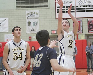 McDonald’s Kenny Greaver, left, watches as teammate Anthony Pugh shoots over Lowellville defender Paolo DePasquale during the first quarter of their Division IV district semifinal Tuesday at the Struthers Fieldhouse. The Blue Devils held off the Rockets, 75-67.