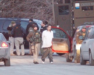 A member of the Mahoning Valley Crisis Response Team leads Phillip Johnson of Youngstown out of a house in the 100 block of East Marion Avenue on Thursday after a standoff.