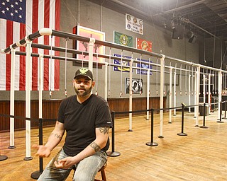 Derrick Dozier, co-owner of Rodeo Music Hall in Austintown, sits in front of what is being called the world’s largest beer bong.