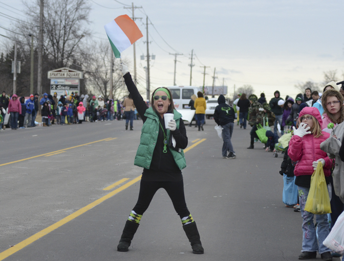 Katie Rickman | The Vindicator.Terra Koontz, 25, of Youngstown waves her flag and cheers as the St. Patrick's Day parade passes by Sunday afternoon.