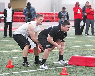 Former Youngstown State football players Kurt Hess, left, and Chris Elkins run through snapping drills Wednesday during Pro Day at YSU’s Watson and Tressel Training Site. Hess and Elkins were among six ex-Penguins who showcased their talents for NFL scouts from the Browns, Steelers, 49ers, Giants and Chargers.