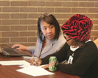 Leigh Greene-Colvin, left, an Access Health Mahoning Valley navigator for the Affordable Care Act health insurance marketplace, helps Gloria Marlowe with her paperwork as she enrolls in the ACA at the Eastern Gateway
Community College campus in Youngstown.