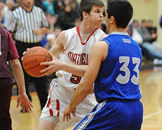 HOWLAND, OHIO - MARCH 25, 2014: Wyatt Ford #5 of Mathews looks to pass the ball while being guarded under the basket by George Chammas #33 of Poland during Tuesday nights Frank Bubba Classic boys basketball all-star game at Howland High School.