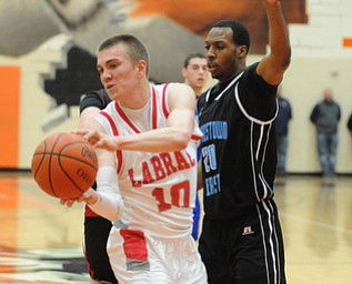 HOWLAND, OHIO - MARCH 25, 2014: Peyton Aldridge #10 of Labrae looks to pass the ball after dribbling into the paint and Terrell McClain of East was guarding during Tuesday nights Frank Bubba Classic boys basketball all-star game at Howland High School.