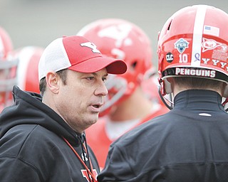 Youngstown State offensive coordinator Shane Montgomery talks to quarterback Ricky Davis between plays during the team’s first practice of 2014 Saturday at YSU’s Stambaugh Stadium. Davis, a redshirt freshman, is one of four players battling this spring to replace Kurt Hess as starting quarterback. The competition continued at Thursday’s practice, which was the Penguins’ first in pads.