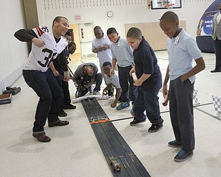 Cook, left, races his Pinewood Derby car with fourth-graders at the school. The boys made and decorated the cars as part of Scoutreach.