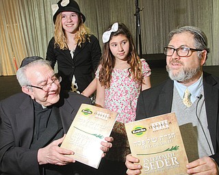 The Rev. George Balasko, left, and Rabbi Joseph Schonberger hold Haggadah, prayer books for the Seder meal, during the pre-Passover event Wednesday night at Stambaugh Auditorium in Youngstown. Sisters D’Ella, 14, and Millie Heschmeyer, 10, participated in the event. Sophia Brooks also sang.