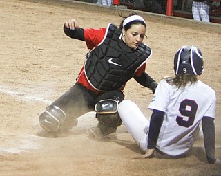 Robert Morris’s Tess Apke kicks up dust as she tries to avoid the tag by Youngstown State catcher Maria Lacatena as she slides into home during the second game of their doubleheader Wednesday at the YSU softball complex. The Penguins lost both games to the Colonials, 6-1 and 6-4.