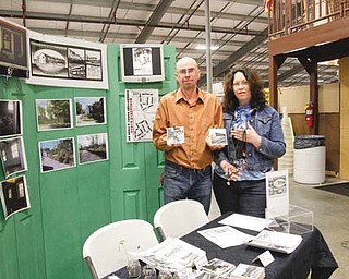 Tim Sokoloff and Linda Gens hold up handmade coasters and necklaces they have for sale at Four Seasons Flea and Farm Market in Youngstown. Sokoloff and Gens are the president and executive director, respectively, of the Iron Soup Historical Preservation Co. They will be selling the items throughout April to bring more former Youngstown Sheet & Tube Co. worker housing units in Campbell out of blight and into tenancy.