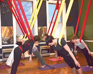 Participants in Jennifer Neal’s aerial yoga class dangle from the ceiling at Eos Whole Fitness located in the Calvin Center for the Arts, 755 Mahoning Ave., Youngstown.