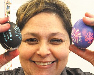Carmelann Maszczak, a teacher at Programs of Promise at Wilson, the Youngstown City School District’s alternative school, shows off Polish-style Easter eggs her students made for the holiday. Below, student Rayshawn Wallace applies wax to a hardboiled egg in the Polish style of coloring Easter eggs.