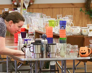Laura McCormick of Niles lines up an array of mugs, cups and glassware on one of the 400 tables in four buildings for this weekend’s Angels for Angels gigantic garage sale. Between 150 and 200 volunteers prepare for the fundraiser set Friday through Sunday at the Canfield Fairgrounds.
