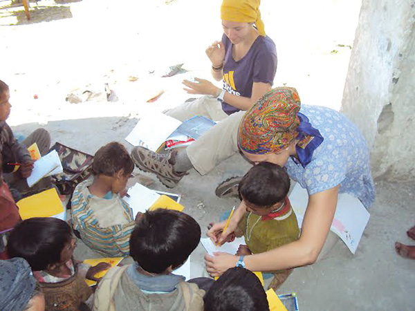 YSU basketball player Heidi Schlegel helps an Indian boy write the letter “A” during her cultural immersion
trip to India last summer. Schlegel’s teammate, Jenna Hirsch, will be part of this year’s trip, which runs May 11 through June 1 and is sponsored by the Coalition for Christian Outreach.