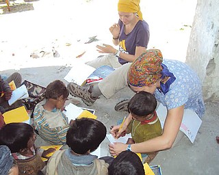 YSU basketball player Heidi Schlegel helps an Indian boy write the letter “A” during her cultural immersion
trip to India last summer. Schlegel’s teammate, Jenna Hirsch, will be part of this year’s trip, which runs May 11 through June 1 and is sponsored by the Coalition for Christian Outreach.