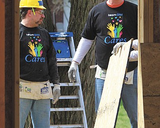 Bruce Thomas of Struthers, above left, and Glenn Johnson of Austintown, president of United Auto Workers Local 1112, move wood while volunteering their time to build the first Habitat for Humanity home in Austintown at 3889 New Road for Marine veteran James Skok. Volunteers were focused on getting the insulation installed and plywood sheets on the roof Thursday.