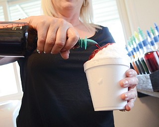 Christine Seman, above, pours cherry-flavored syrup over shaved ice at her Sno Castle location, right, on Youngstown Poland Road in Struthers. This season is Seman’s 22nd running the business, which is open from noon to 9 p.m. daily. It typically opens for the season not long after Easter, then closes a couple of weeks after
school resumes.